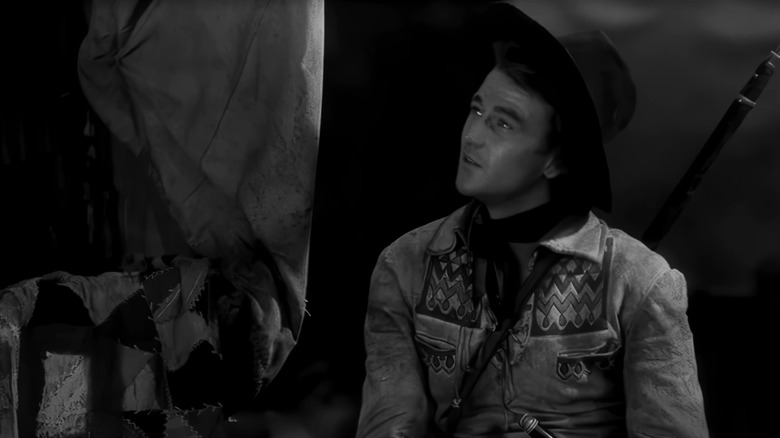 John Wayne's Breck Coleman looks up as he sits down in The Big Trail