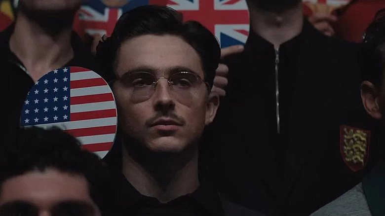 Marty Mauser holding a paddle with an American flag on it in Marty Supreme