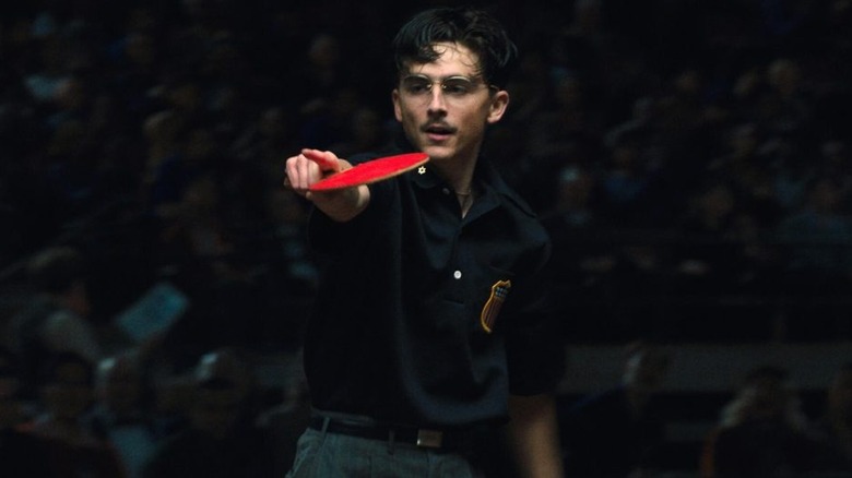 Marty pointing with a ping pong paddle in Marty Supreme