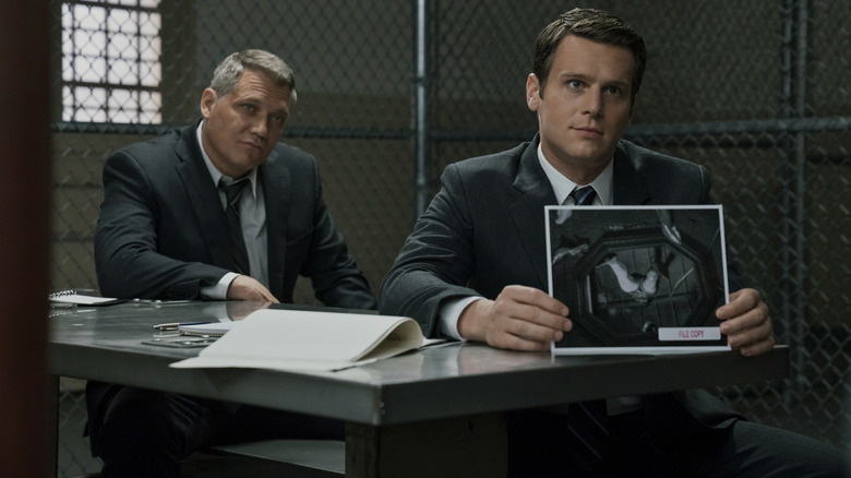 Jonathan Groff as Holden Ford and Holt McCallany as Bill Tench seated in an interrogation room in Mindhunter