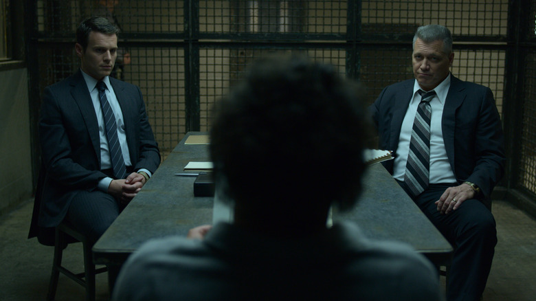Jonathan Groff as Holden Ford and Holt McCallany as Bill Tench seated in an interrogation room in Mindhunter