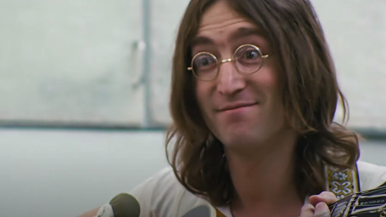 John Lennon smirking while holding a guitar in The Beatles: Get Back