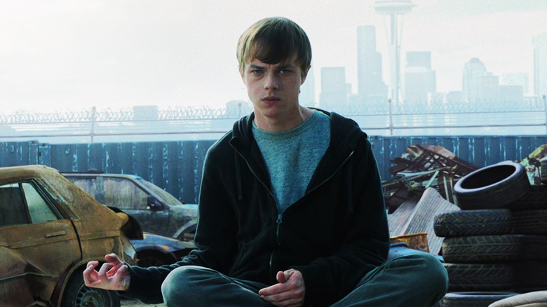 Dane DeHaan's Andrew sits cross legged and makes a gesture with his hand in Chronicle