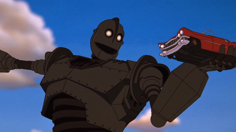 The Iron Giant holding a car in one hand in The Iron Giant