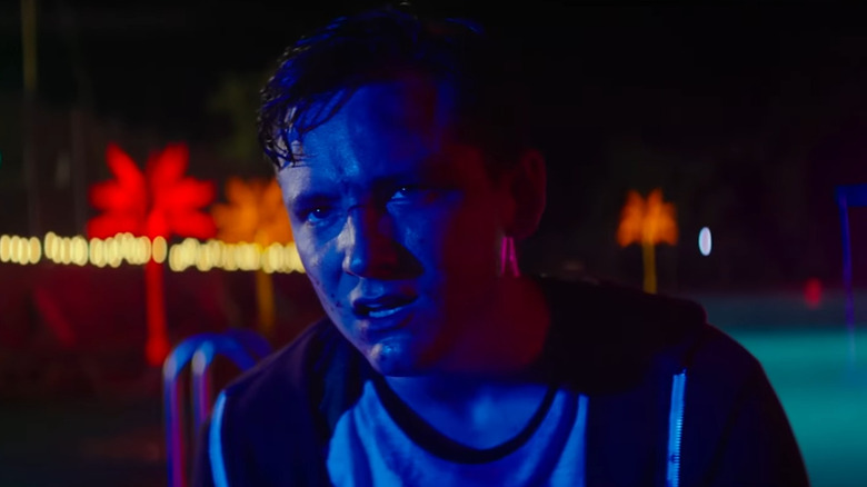 Luke bathed in blue light at the trailer park pool in The Strangers: Prey at Night
