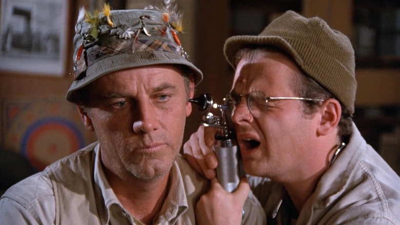 Gary Burghoff as Radar inspecting McLean Stevenson as Henry with an otoscope in M*A*S*H