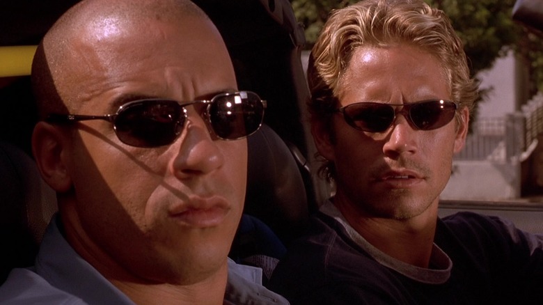 Vin Diesel as Dom and Paul Walker as Brian looking at someone in the car next to them with their sunglasses on in The Fast and the Furious