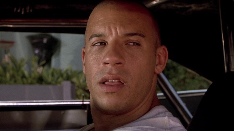 Vin Diesel as Dom Toretto looking out the window of his car in The Fast and the Furious