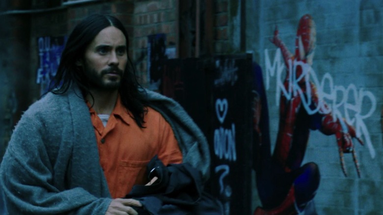 Michael walking past a graffiti picture of Spider-Man in Morbius