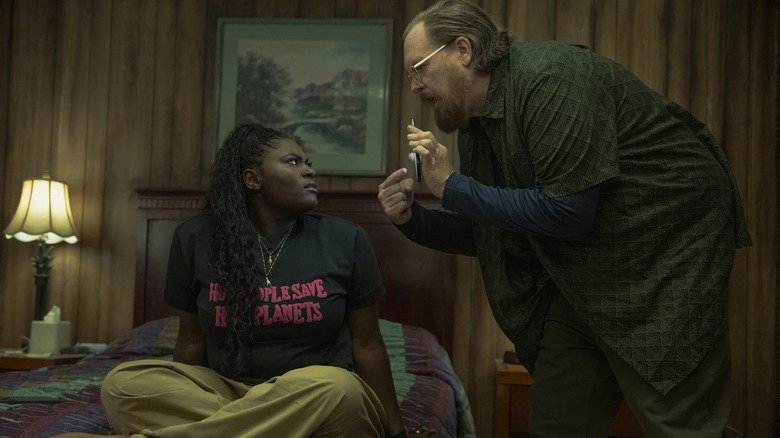 Danielle Brooks as Leota Adebayo and Steve Agee as John Economos having a discussion about a picture on his phone in Peacemaker