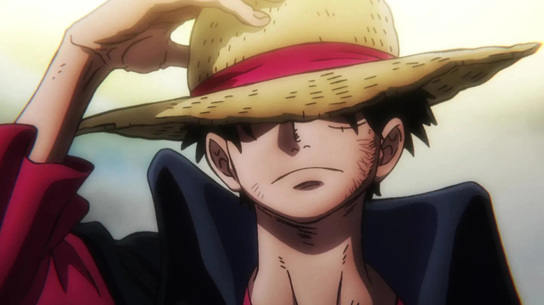 Luffy puts his hand on his straw hat to show how cool he is in One Piece