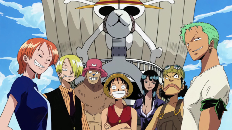 The Straw Hat crew smiles in front of their ship the Going Merry in One Piece