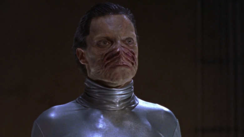Alex Zahara's Xe'ls stands against a black background in Stargate SG-1