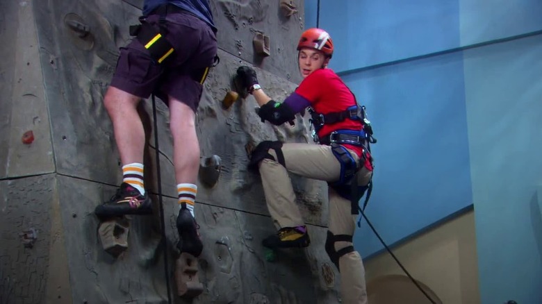 A nervous Sheldon Cooper scales a climbing wall on The Big Bang Theory.