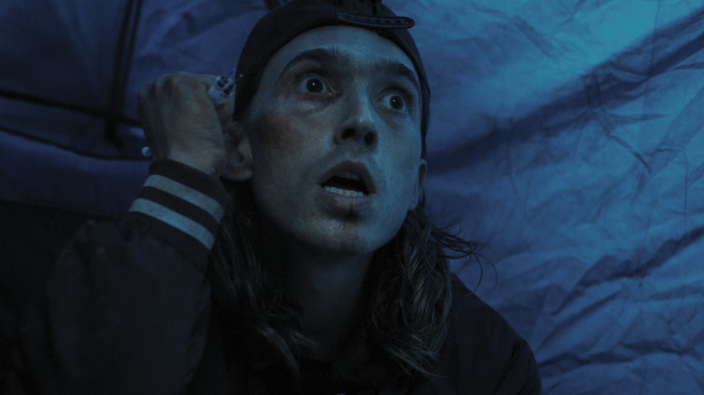Austin Abrams hiding in a tent holding a batch of syringes