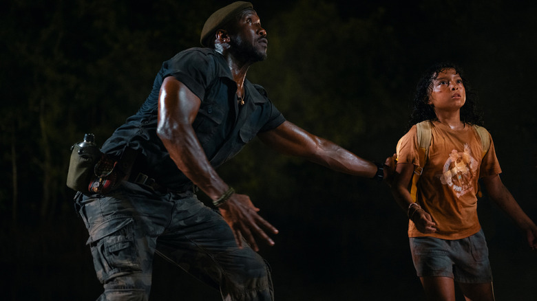 Mahershala Ali as Duncan Kincaid protecting Audrina Miranda as Isabella Delgado from a dinosaur in Jurassic World Rebirth