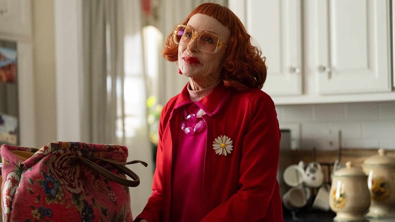 Gladys standing in Marcus' kitchen smiling next to her handbag in Weapons