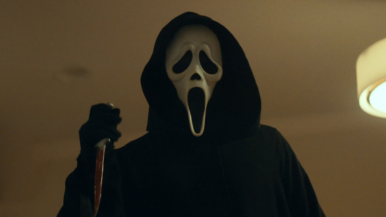 Ghostface holding a bloody knife in the kitchen in Scream (2022)