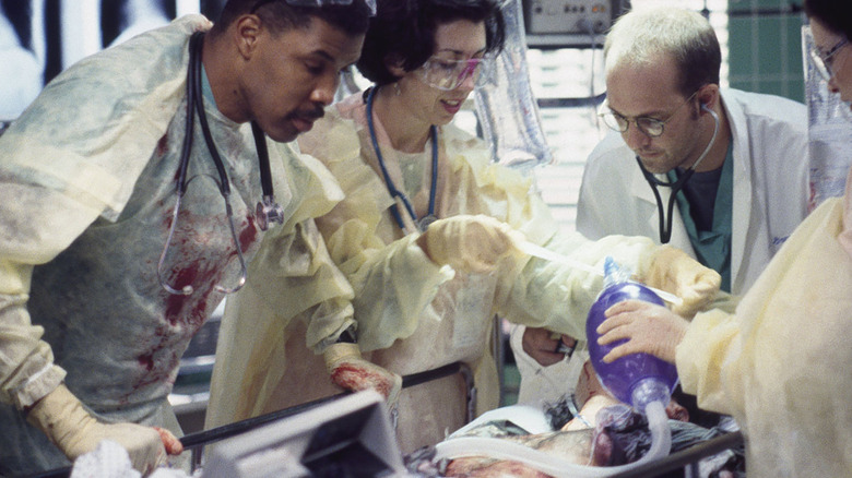 Three doctors looking over a patient on the TV series ER.