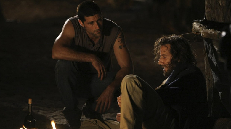 Jack se agacha para falar com Desmond bêbado na praia na 2ª temporada de Lost