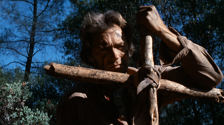 జోసీ వేల్స్ ది అవుట్‌లా జోసీ వేల్స్‌లో క్రాస్‌పై వాలుతున్నాడు