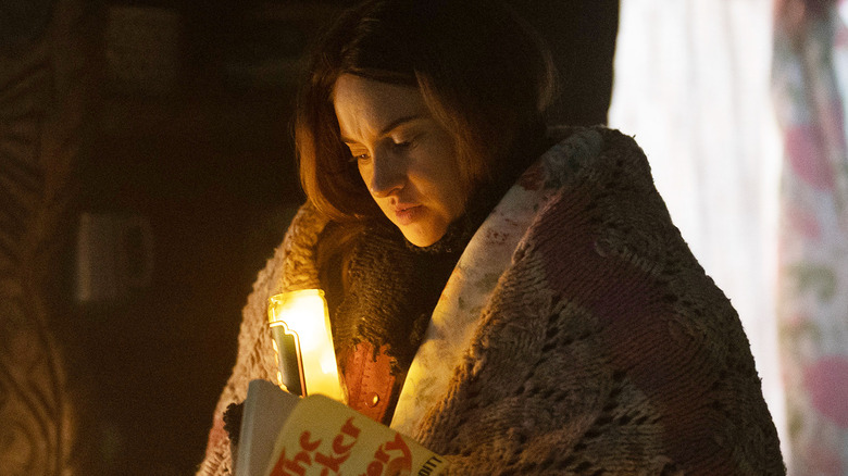 Shailene Woodley as Annie wrapped in a blanket and reading a book by candlelight in Paradise season 2