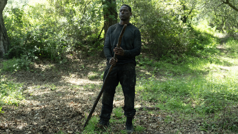 Sterling K. Brown as Xavier Collins standing in a forest with a walking stick in Paradise season 2