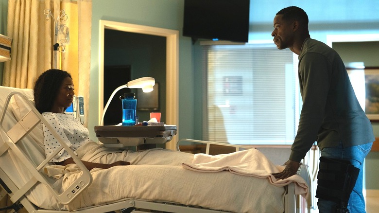 Xavier standing at the base of Teri's hospital bed in season 2 of Paradise