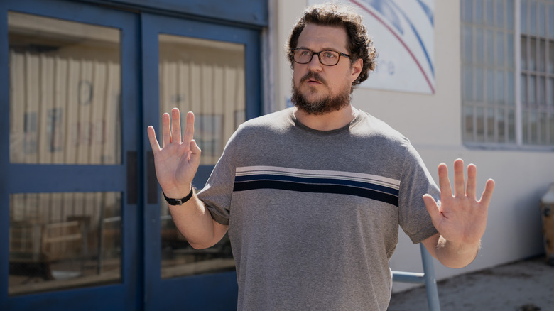 Gary raises his hands in the air in alarm in Paradise