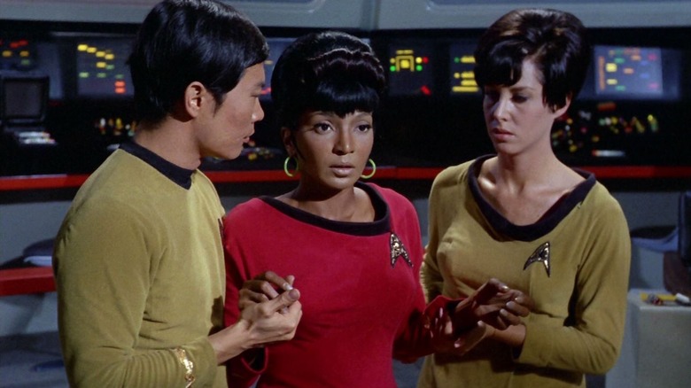Uhura, confused, being held by Sulu and another officer on Star Trek