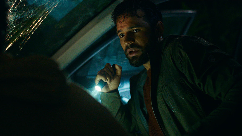 Jacob Scipio as Tyler holding a flashlight while sitting in a crashed car in Passenger