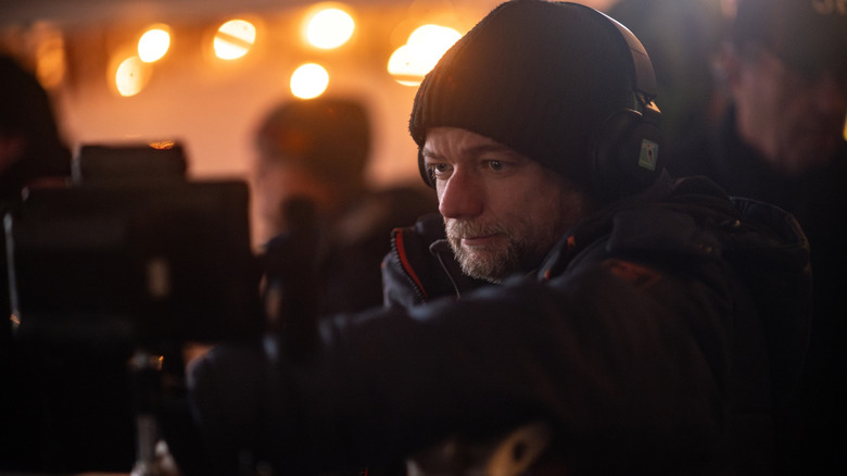 Director André Øvredal standing by a camera in front of orange lights on the set of Passenger