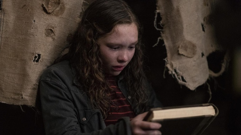 Zoe Colletti as Stella looking at a book in Scary Stories to Tell in the Dark