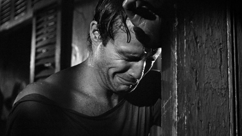 Marlon Brando as Stanley Kowalski soaking wet and sobbing while leaning against a door in A Streetcar Named Desire