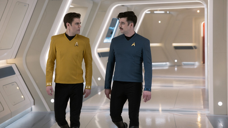 Paul Wesley as James T. Kirk walking down a brightly-lit hallways next to Dan Jeannotte as Sam Kirk in Star Trek: Strange New Worlds