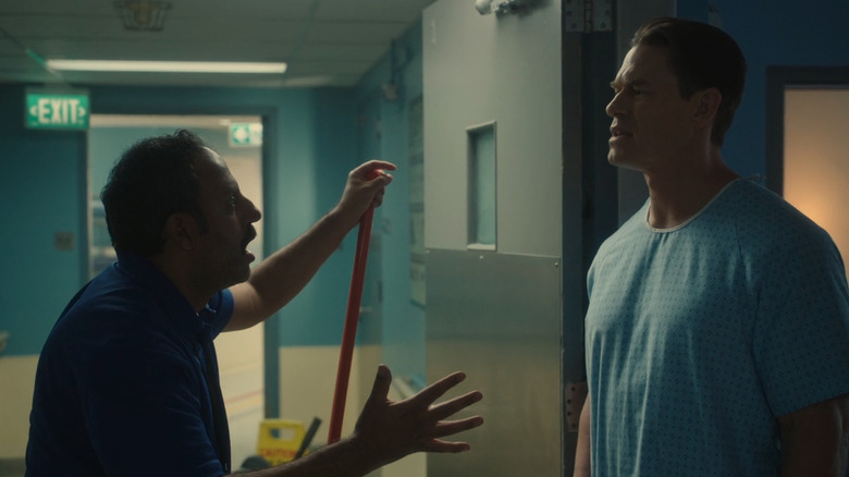 Rizwan Manji as Jamil the janitor talking with John Cena as Peacemaker in a hospital hallway in Peacemaker season 1