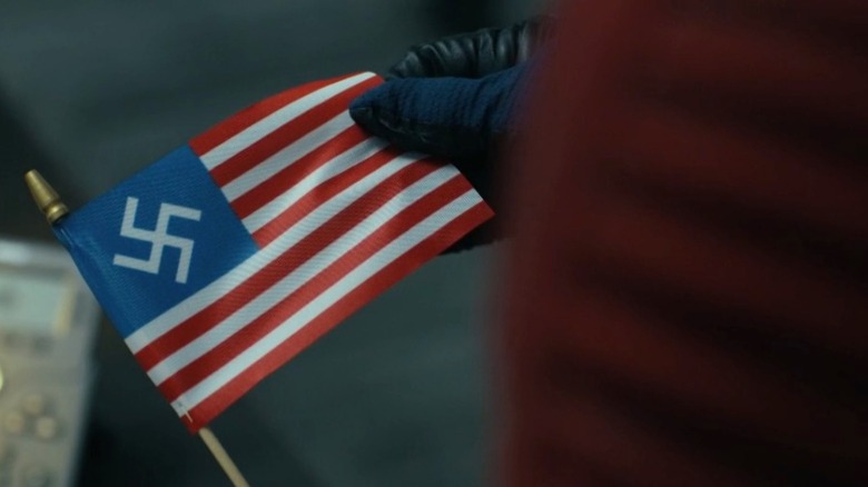 Peacemaker holding a US Nazi flag in "Peacemaker" season 2, episode 6, "Ignorance Is Chris"