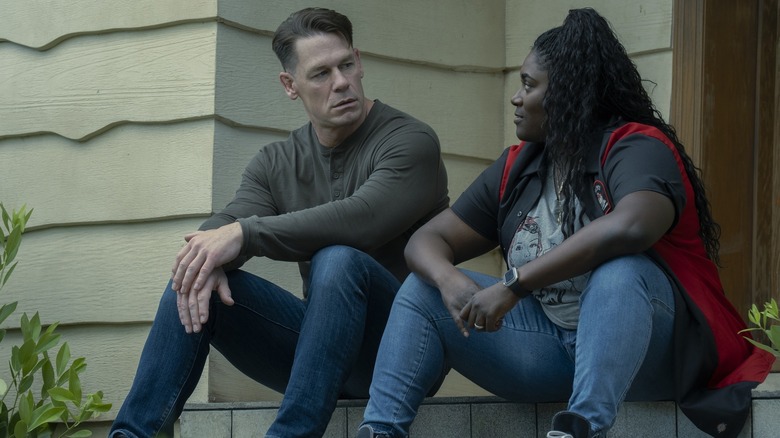 John Cena as Peacemaker and Danielle Brooks as Adebayo sitting on Peacemaker's front porch