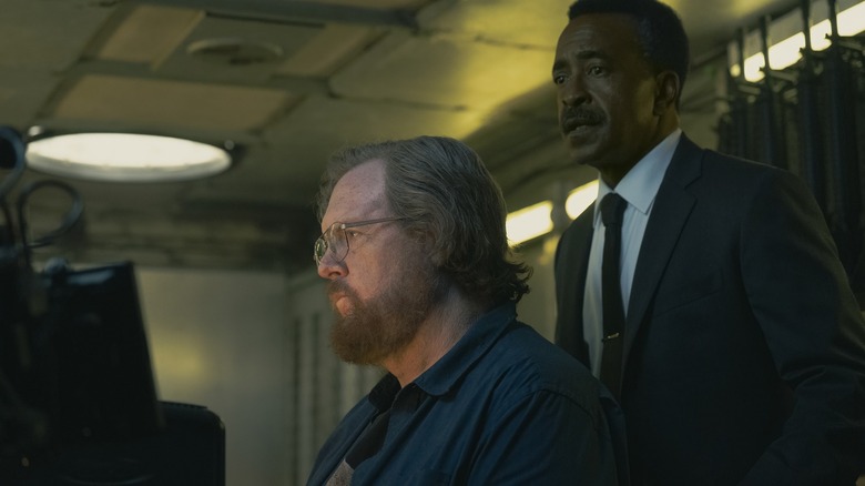 Steve Agee as John Economos looking peeved as Tim Meadows as Langston Fleury looks on in Peacemaker season 2