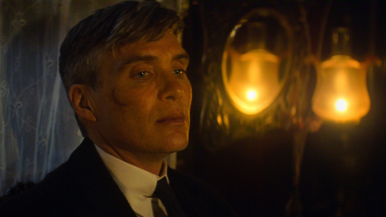 Cillian Murphy as Tommy Shelby standing in a dark room and looking off screen in Peaky Blinders: The Immortal Man