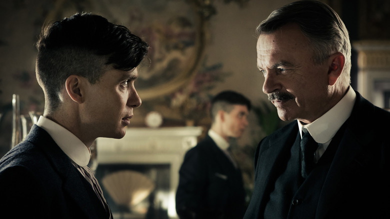 Cillian Murphy as Tommy Shelby staring down Sam Neill as Major Campbell at a dinner party in Peaky Blinders