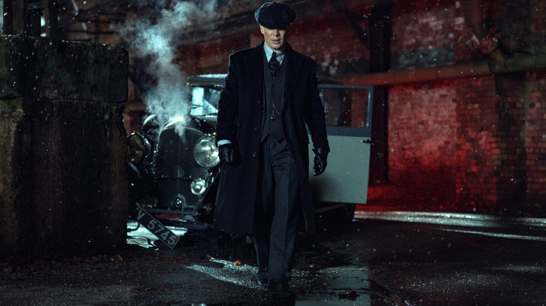 Cillian Murphy as Tommy Shelby walking away from a crashed car on a street in Peaky Blinders: The Immortal Man
