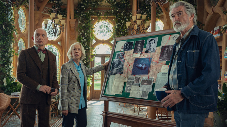 Ibrahim, Elizabeth, and Ron in front of a murder board in The Thursday Murder Club