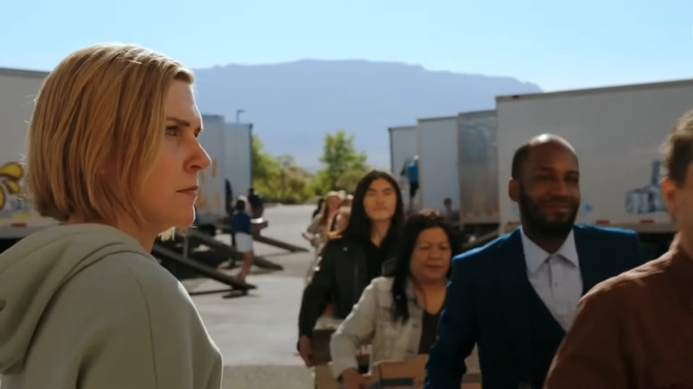 Rhea Seehorn as Carol Sturka seated in an airplane and leaning into the aisle in Pluribus