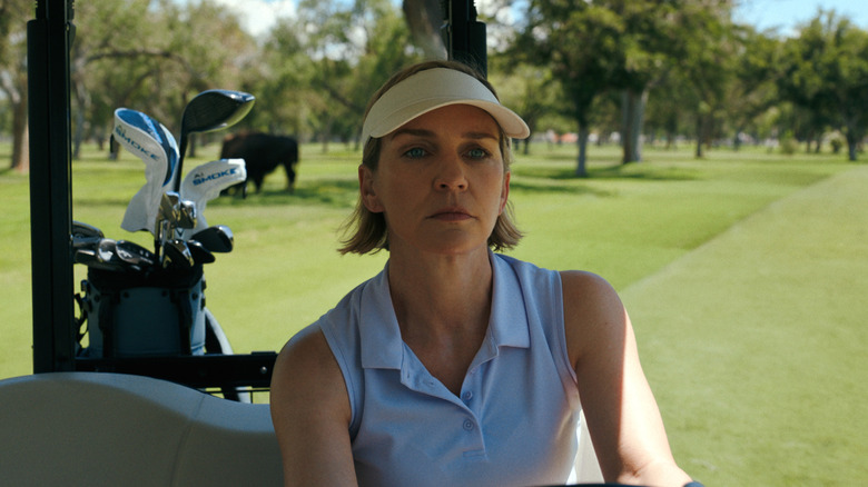 Rhea Seehorn's Carol Sturka driving a golf cart with a buffalo grazing behind her on Pluribus