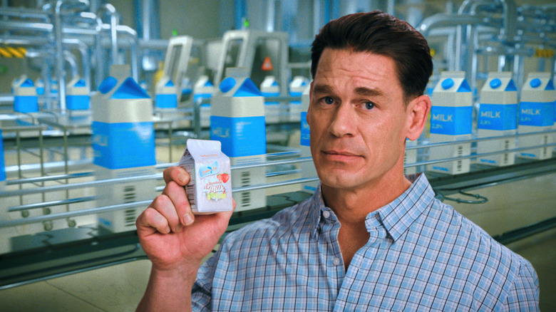 John Cena's hive mind version holding up a carton of HDP on Pluribus