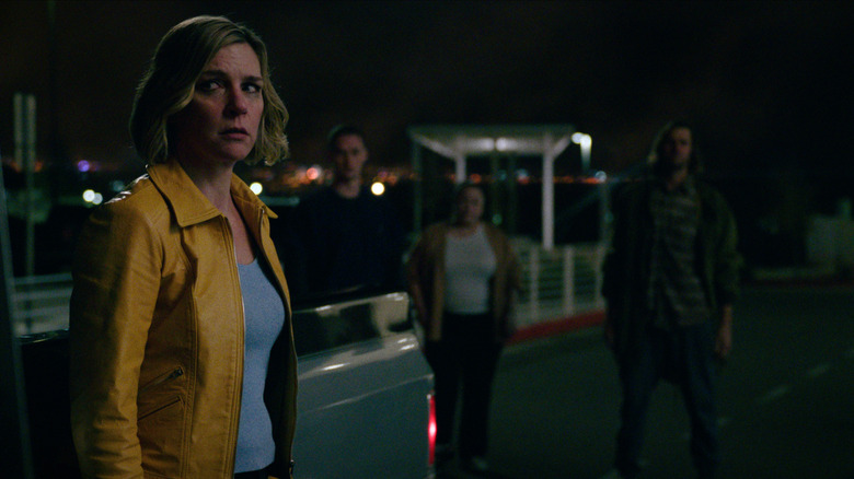 Rhea Seehorn as Carol Sturka looking worriedly at several people surrounding her in Pluribus