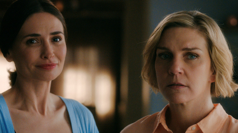 Karolina Wydra as Zosia smiling and standing next to Rhea Seehorn as Carol Sturka looking concerned in Pluribus