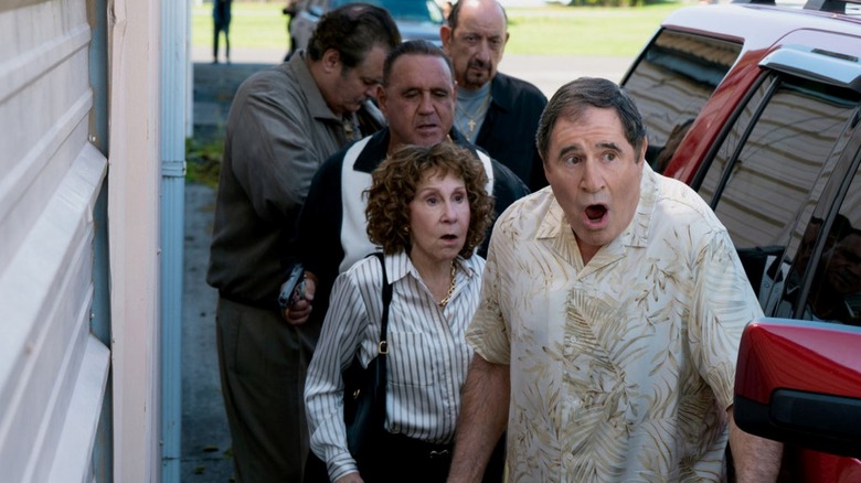 Rhea Perlman as the crime boss Beatrix and Richard King as her husband Jeffrey surrounded by henchmen in Poker Face
