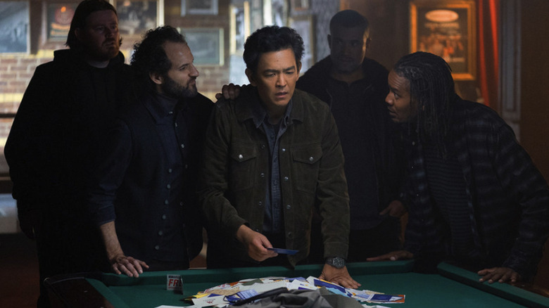 John Cho's character in Poker Face season 2 is surrounded by intimidating looking guys hovering around a pool table